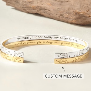 Può includere: Un braccialetto dorato e bianco con un design floreale e l'iscrizione "my maid of honor today, my sister forever maid of honor for a day, best friend for life". Il braccialetto ha spazio per un messaggio personalizzato.