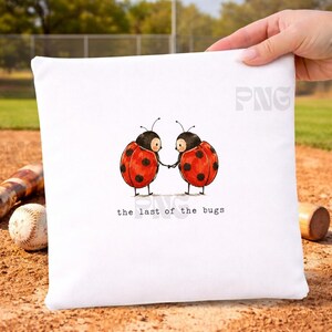Puede incluir: Una bolsa cuadrada de tela blanca con una ilustración central de dos mariquitas rojas con puntos negros tomadas de la mano. Debajo de las mariquitas, el texto "the last of the bugs" aparece en una fuente negra sencilla, en minúsculas y estilo máquina de escribir.