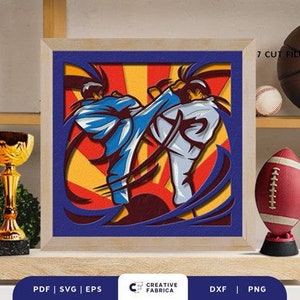 May include: A digital illustration of two martial artists in mid-air, performing a karate kick. The background is a red, yellow, and blue color scheme with a sunburst pattern. The image is framed in a wooden frame.