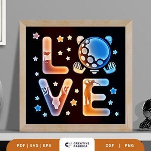 May include: A framed image with a black background and the word "LOVE" spelled out in a stylized font. The letters are outlined in orange and blue and have a glow effect. The "O" in "LOVE" is a golf ball with a golfer silhouette in front of it. The background is decorated with stars.