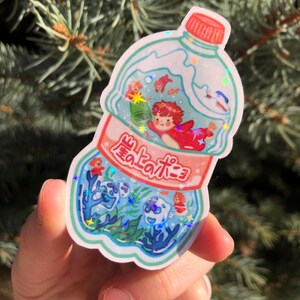 K&ouml;nnte beinhalten: Eine durchsichtige Plastikflasche mit einem roten und wei&szlig;en Etikett, auf dem in Japanisch "海の宝石" steht. Die Flasche ist mit Wasser gef&uuml;llt und enth&auml;lt verschiedene bunte Fische und Meeresbewohner. Die Flasche ist von einem wei&szlig;en Rand umgeben.
