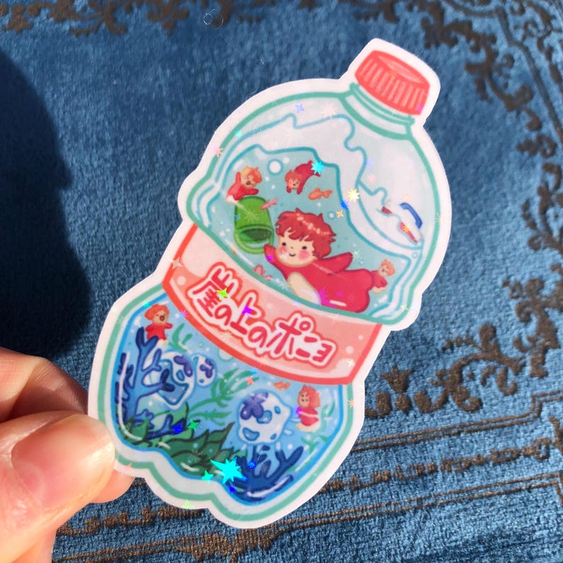 K&ouml;nnte beinhalten: Eine durchsichtige Plastikflasche mit rotem Verschluss und einem rosa Etikett, auf dem "海のラムネ" in japanischer Schrift steht. Die Flasche ist mit blauem Wasser gef&uuml;llt und enth&auml;lt kleine, bunte Figuren, darunter einen roten Fisch, einen gr&uuml;nen Frosch und eine blaue Qualle. Die Flasche ist von einem wei&szlig;en Rand umgeben.