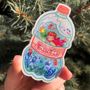 K&ouml;nnte beinhalten: Ein Aufkleber mit einer durchsichtigen Plastikflasche mit rotem Verschluss, gef&uuml;llt mit einer blauen und gr&uuml;nen Ozeanszene. Die Flasche tr&auml;gt den japanischen Text "海のポニ" auf der Seite. In der Flasche befinden sich kleine Fische und eine Meerjungfrau.