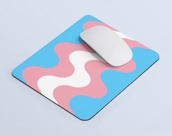 Puede incluir: Una alfombrilla de ratón azul y rosa con un patrón ondulado. Un ratón de ordenador blanco está encima de la alfombrilla de ratón.