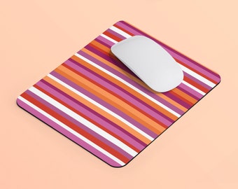 Puede incluir: Una alfombrilla de ratón a rayas con un ratón de ordenador blanco en la parte superior. La alfombrilla de ratón tiene rayas horizontales en tonos de rosa, naranja y morado.