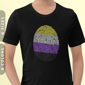 May include: Black t-shirt featuring a fingerprint design in yellow, white, purple, and black. The fingerprint symbolises the non-binary pride flag.