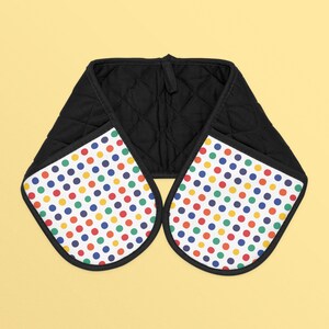 May include: Black quilted oven mitt with a white polka dot pattern in red, blue, green, yellow, and orange. The mitt has a loop for hanging and is designed to protect hands from heat when handling hot cookware.