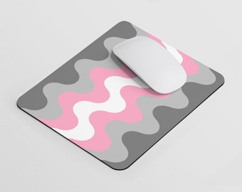 Puede incluir: Una alfombrilla de ratón con un patrón ondulado rosa, gris y blanco con un ratón de ordenador blanco en la parte superior.