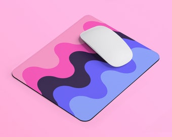 Puede incluir: Una alfombrilla de ratón colorida con un patrón ondulado en tonos de rosa, azul y morado. Un ratón de ordenador blanco está encima de la alfombrilla.