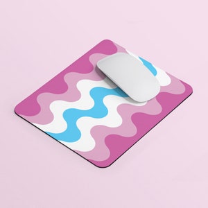 Peut inclure: Un tapis de souris à motifs ondulés rose et bleu avec une souris d'ordinateur blanche sur le dessus.