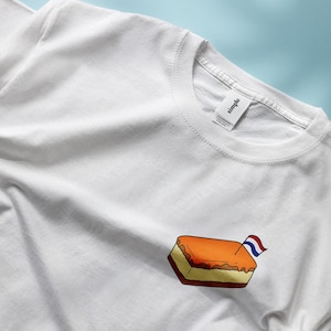 Pu&ograve; includere: T-shirt bianca con una piccola grafica di un dolce olandese, un pasticcino rettangolare con copertura arancione e una piccola bandiera olandese. La maglietta &egrave; in materiale morbido.