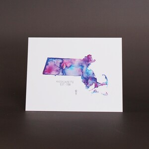 Könnte beinhalten: Aquarellmalerei des Bundesstaates Massachusetts in Blautönen, Lila und Rosa. Der Name des Bundesstaates und das Gründungsjahr "MASSACHUSETTS EST 1788" sind in Weiß unterhalb der Umrisse geschrieben.