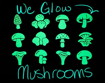 May include: A black graphic print featuring twelve distinct light green mushroom illustrations arranged in a grid. The text "We Glow" appears at the top left with an arrow pointing to a mushroom, and the word "Mushrooms" is written at the bottom.