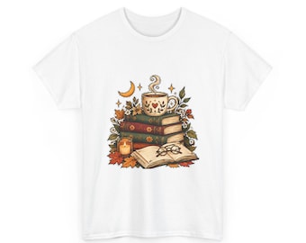 May include: A white t-shirt featuring a central graphic of a stack of three books topped with a steaming mug, a lit candle, and an open book with glasses. The illustration includes autumn leaves, small flowers, and a crescent moon in warm tones.