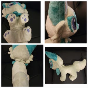 May include: A plush toy in the shape of a fox with white fur, blue ears, and purple paw pads. The fox is sitting on a sofa.