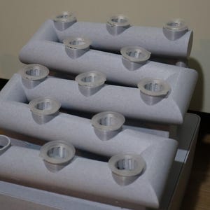 Peut inclure: Un pot de fleurs en plastique gris &agrave; plusieurs &eacute;tages avec des trous ronds pour la plantation. Le pot est con&ccedil;u pour &ecirc;tre empil&eacute; et a un style moderne et minimaliste.