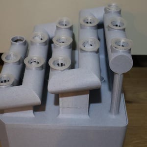 Peut inclure: Un objet gris imprim&eacute; en 3D avec plusieurs ouvertures circulaires. L'objet est con&ccedil;u pour contenir de petits objets, tels que des plantes ou des semis.
