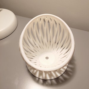 May include: White ceramic bowl with a lattice design. The bowl is on a white base.