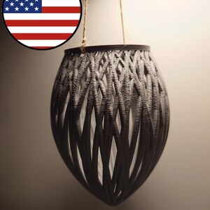 May include: A gray hanging planter made of woven plastic. The planter is suspended from a natural twine cord.