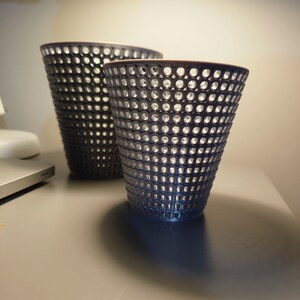 May include: Two grey, open-weave, cone-shaped vases. The larger vase is behind the smaller vase.
