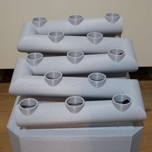 Peut inclure: Un support de plantes gris &agrave; plusieurs niveaux avec 12 pots ronds &agrave; ouverture sup&eacute;rieure. Le support est en plastique textur&eacute; et a une base carr&eacute;e.