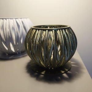 May include: Two decorative woven candle holders, one white and one gold. The gold holder has a round base.