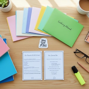May include: A selection of pastel-coloured envelopes, including pink, yellow, green, blue, and white, with the words "Looking Ahead" on a green envelope. Also features two information cards, a "You got this" sticker, a coffee cup, and spectacles.