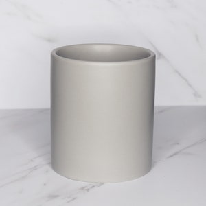May include: A light gray ceramic cylindrical container, perfect for holding brushes, pencils, or other small items.
