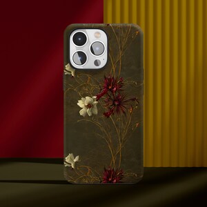 May include: A phone case with a floral design. The case is dark green with gold accents and features white and red flowers.