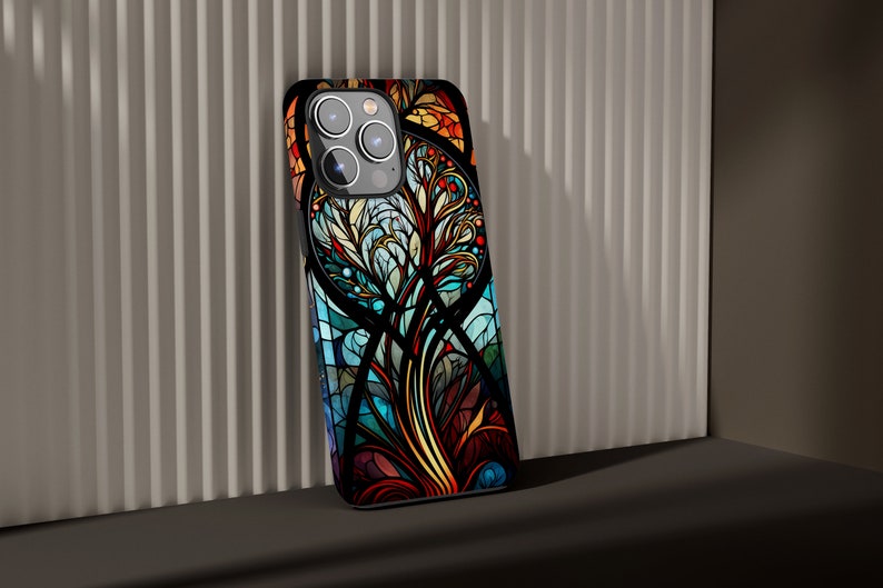 May include: A black phone case with a colorful stained glass design featuring a tree with blue, green, yellow, orange, and red accents.