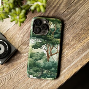 Peut inclure: Coque de smartphone avec une for&ecirc;t &agrave; l'aquarelle, repr&eacute;sentant des arbres verts et une atmosph&egrave;re l&eacute;g&egrave;re et a&eacute;r&eacute;e. Le bo&icirc;tier a une finition brillante et un module cam&eacute;ra sombre. Le design &eacute;voque la nature et la tranquillit&eacute;.