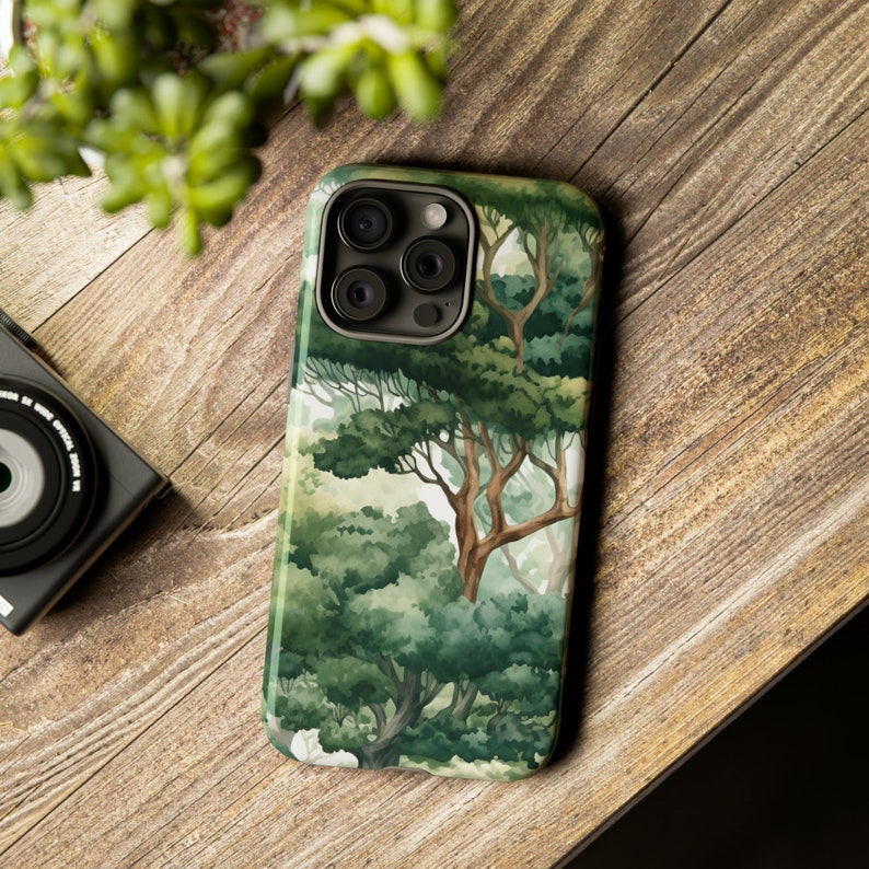 Peut inclure: Coque de smartphone avec une for&ecirc;t &agrave; l'aquarelle, repr&eacute;sentant des arbres verts et une atmosph&egrave;re l&eacute;g&egrave;re et a&eacute;r&eacute;e. Le bo&icirc;tier a une finition brillante et un module cam&eacute;ra sombre. Le design &eacute;voque la nature et la tranquillit&eacute;.