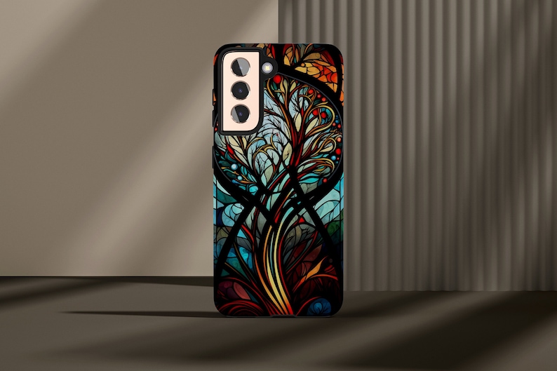 May include: A black phone case with a colorful stained glass design featuring a tree with intricate branches and leaves. The design is in shades of blue, green, yellow, orange, and red.