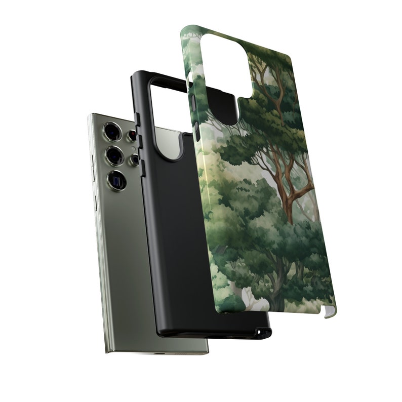 Peut inclure: Un smartphone avec un &eacute;tui noir et un &eacute;tui s&eacute;par&eacute; avec une peinture &agrave; l'aquarelle d'une sc&egrave;ne de for&ecirc;t avec des arbres verts et des troncs bruns. Le t&eacute;l&eacute;phone est argent&eacute;.