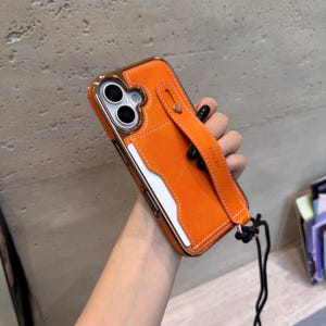 May include: Orange phone case with a gold-colored frame and a matching strap. The case has a card slot and a stitched design. The strap has the word "VIETAO" printed on it.