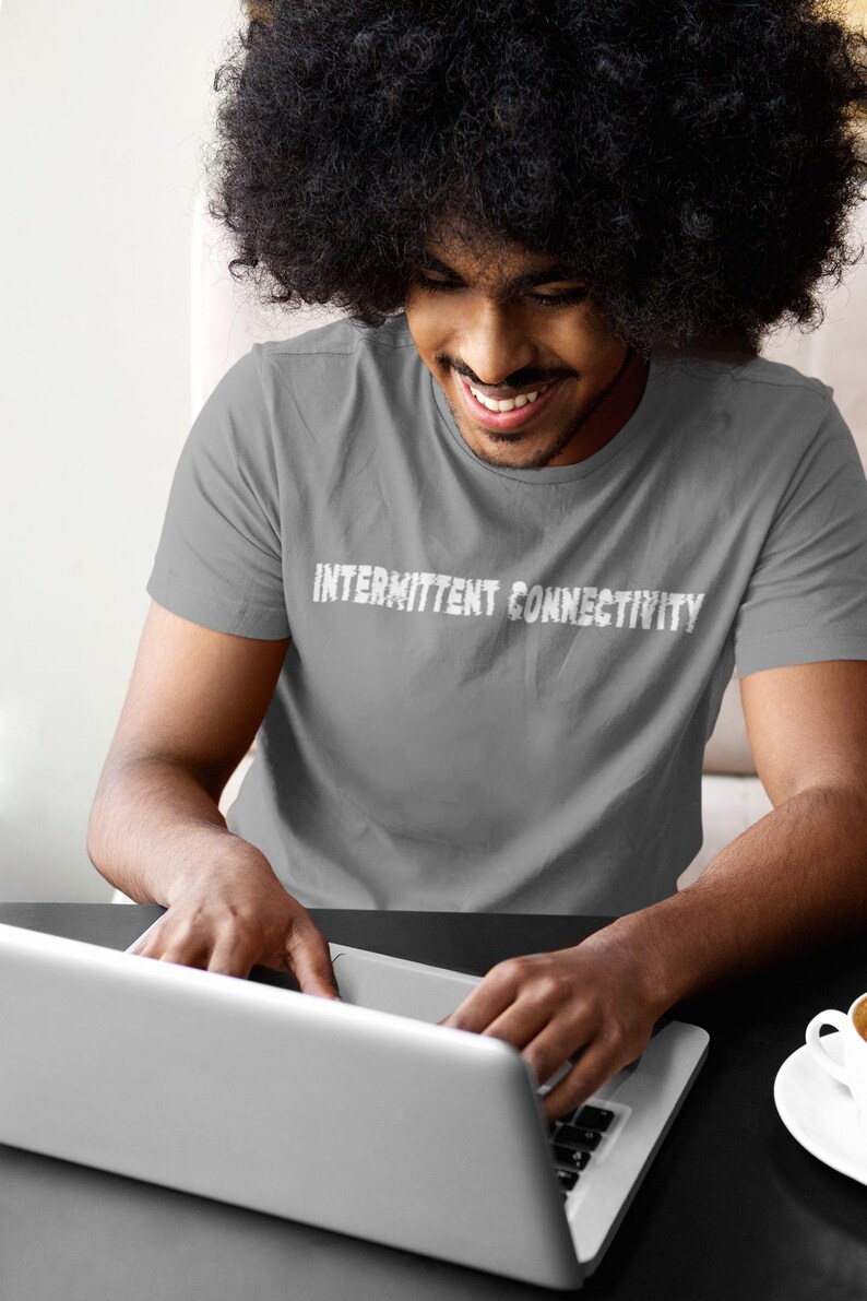 Puede incluir: Una persona con una camiseta gris con el texto "Intermittent Connectivity" impreso en la parte delantera, usando un ordenador port&aacute;til.