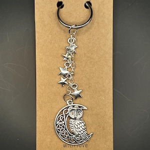 Könnte beinhalten: Silberfarbener Schlüsselanhänger mit einem Mond mit Eulen-Design und einer Kette aus Sternen. Der Schlüsselanhänger ist an einer braunen Karte mit den Worten "with love" und einem kleinen roten Herz befestigt.