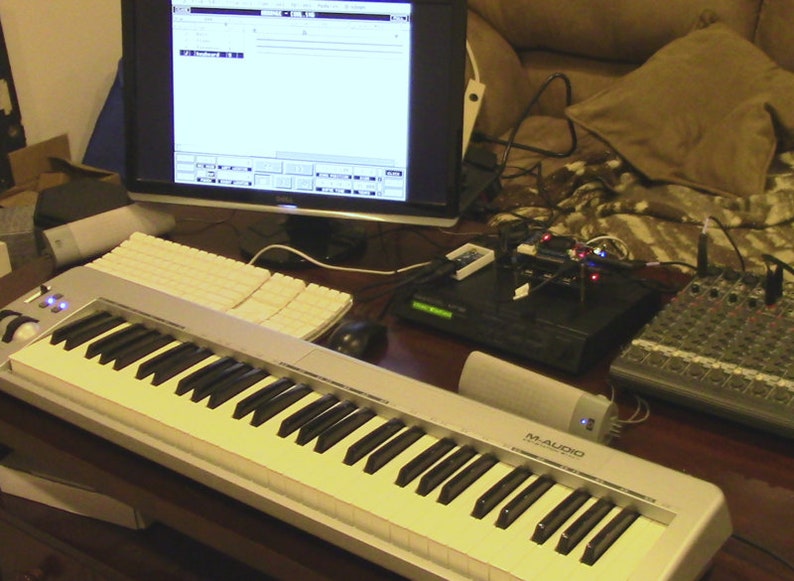 May include: A white MIDI keyboard with black keys and a blue light on the left side. The keyboard is labeled "M-AUDIO Keystation 49e".