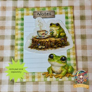 Frog sticker placed on a small gingham notepad labeled “Notes,” featuring a smiling frog illustration below and text indicating notepad sold separately.
