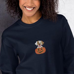 Unisex embroidered sweatshirt featuring a puppy inside a Halloween pumpkin. Comfortable, fun, and adorable Halloween sweatshirt.