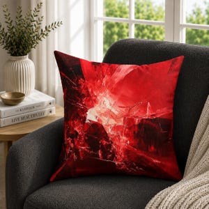 May include: A square throw cushion featuring a vibrant, abstract design of shattered glass in deep shades of crimson and scarlet red. The pattern displays sharp, angular lines and fragmented light reflections, creating a high-contrast visual effect.