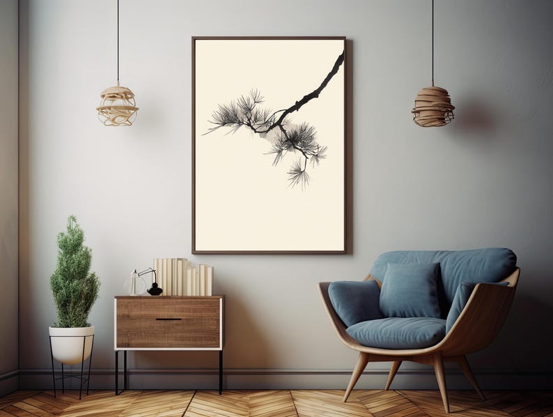 May include: A framed wall art print featuring a black ink illustration of a pine tree branch with needles against a solid cream background. The artwork is displayed in a dark brown frame, centered on a light gray wall above a wooden cabinet.