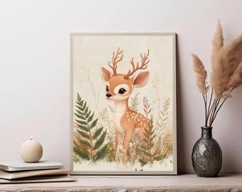 May include: A framed wall art print featuring a light brown fawn with white spots and small antlers standing amidst green ferns and tall grasses. The illustration uses a soft, neutral color palette with cream and beige tones throughout the scene.