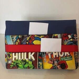 Può includere: Un portafoglio rettangolare con pannelli di fumetti di supereroi Marvel. Il portafoglio ha una parte superiore blu navy, una striscia rossa e dettagli bianchi. I personaggi dei fumetti includono Hulk, Thor e Spider-Man.