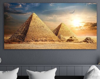 May include: A panoramic photograph of the Great Pyramids of Giza in Egypt, with a sunset sky in the background. The pyramids are made of golden stone and are surrounded by sand.