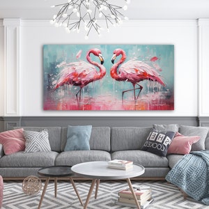 May include: A painting of two pink flamingos standing in a shallow body of water. The flamingos are facing each other and their heads are touching. The painting is in a modern living room setting, hanging above a gray couch with pillows.