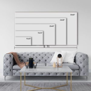 May include: A visual representation of different canvas print sizes, ranging from 10x20 inches to 30x60 inches. The sizes are displayed on a white wall with a gray couch and a coffee table in the foreground.