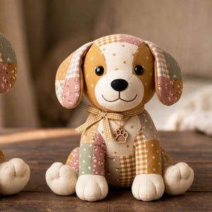 May include: A stuffed dog toy made of patchwork fabric in shades of tan, brown, and muted green with star, floral, and gingham patterns. The dog has black button eyes, a black nose, a gingham ribbon around its neck, and a wooden paw print charm.