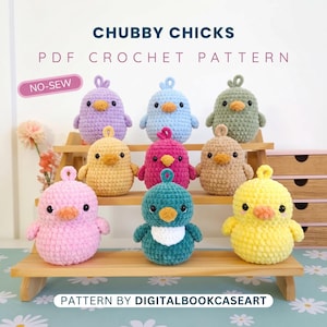 May include: Nine crocheted plush chicks in various colours including purple, blue, green, yellow, pink, and teal, each with a small loop on top, black eyes, and an orange beak. The text reads CHUBBY CHICKS PDF CROCHET PATTERN NO-SEW and PATTERN BY DIGITALBOOKCASEART.