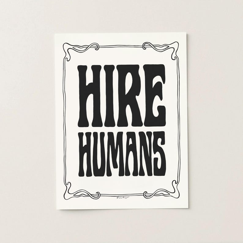A black and white art print of the words HIRE HUMANS in a hand-lettered art nouveau style within a decorative art nouveau border.